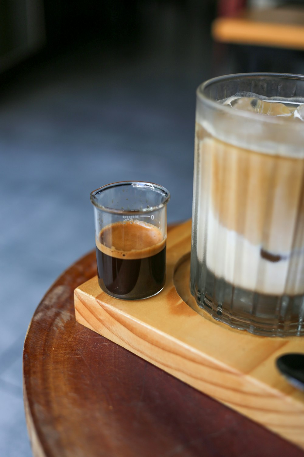 a glass of liquid sitting on top of a wooden tray