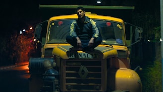a man sitting on top of a yellow truck