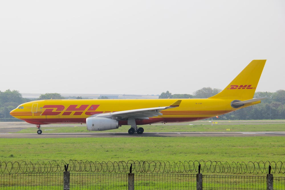 a dhl airplane on the runway at an airport