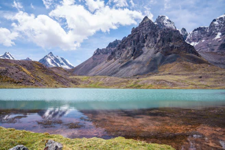 a lake surrounded by mountains under a blue sky