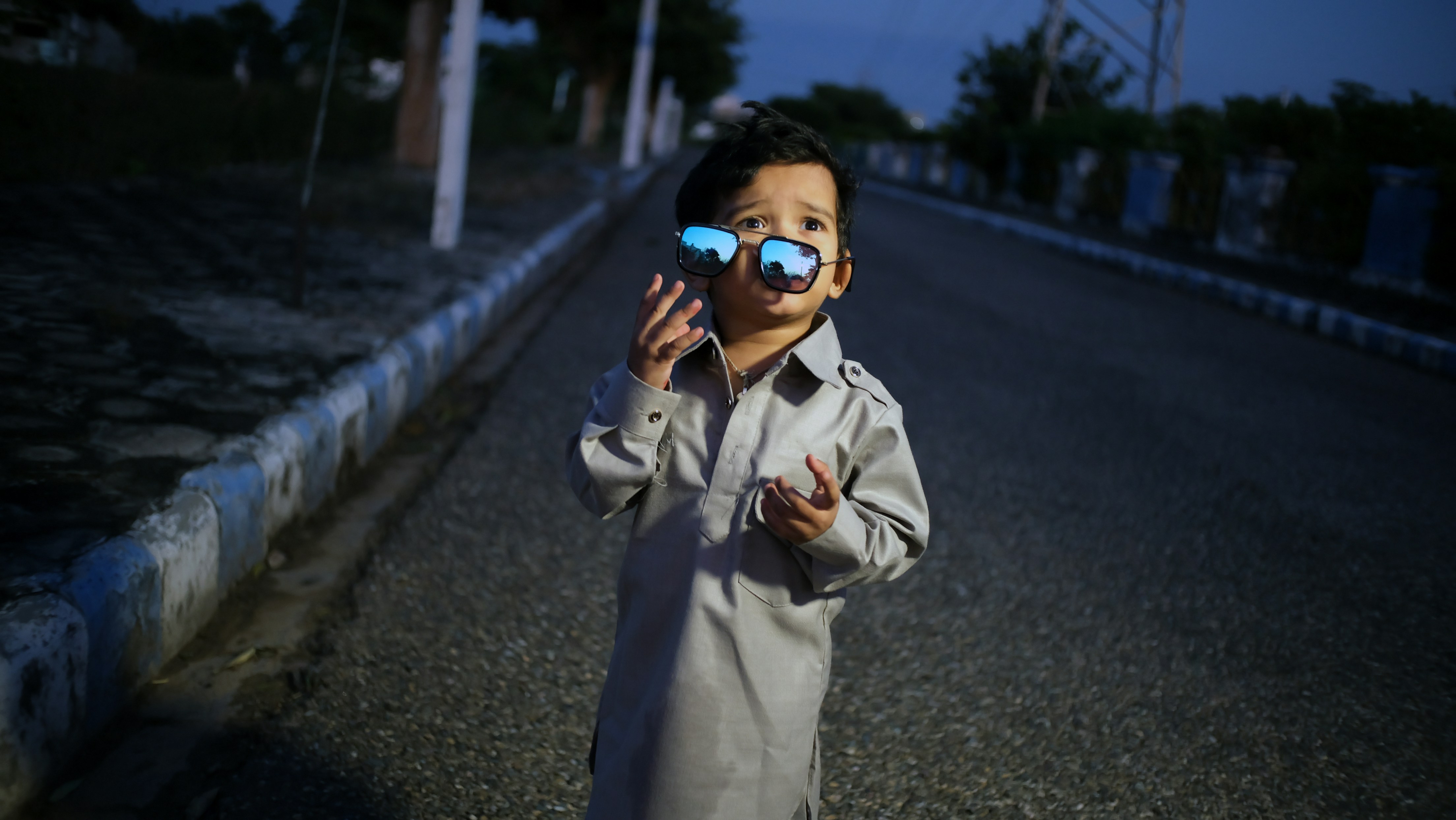a little boy standing on the side of a road