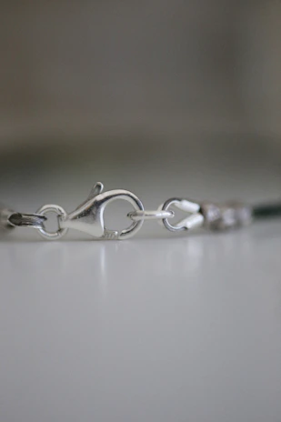 Macro shot of a delicate clasp detail on a gold-plated bracelet, highlighting smooth finish and craftsmanship.