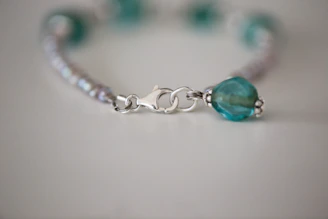 Close-up of a handwoven bracelet with 950 silver details on a wooden surface.