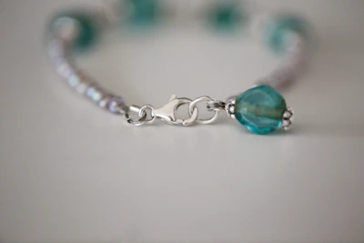 Close-up of a handwoven bracelet with 950 silver details on a wooden surface.