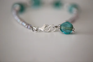 Macro shot showing the polish and clasp detail of a delicate bridal bracelet on slate grey surface