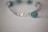 A close-up photo of a custom-made beaded bracelet featuring clear crystal beads and a personalized nameplate.
