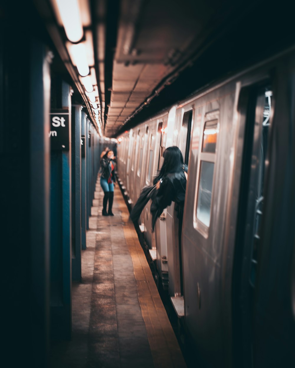 two people standing on a subway platform next to a train