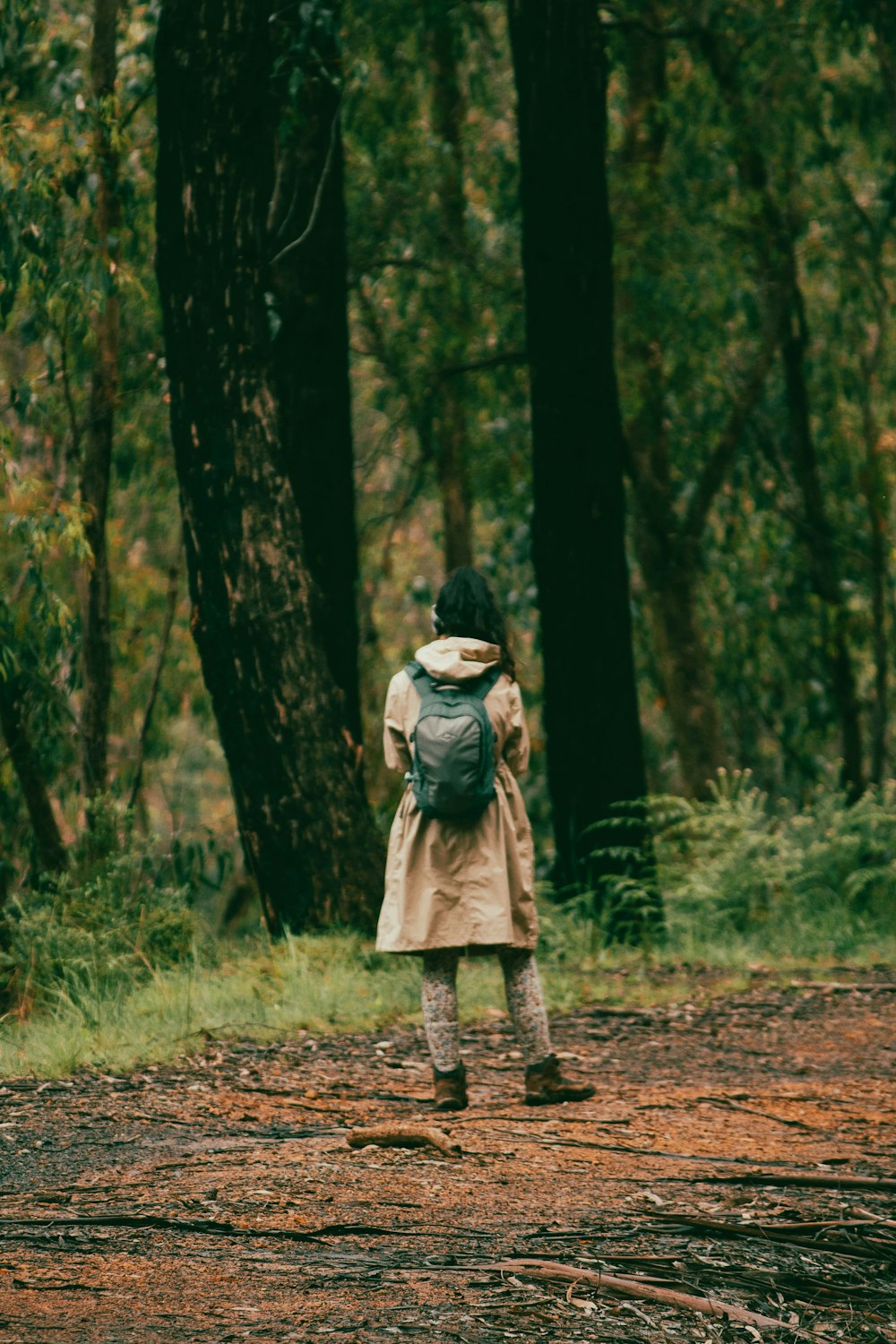 a woman with a backpack walking through a forest