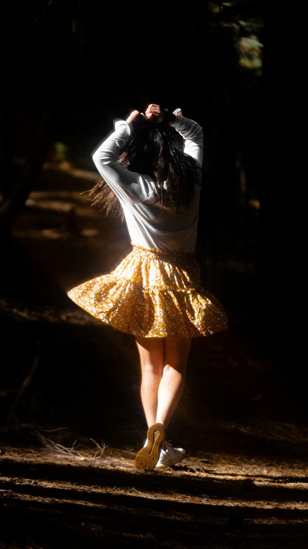 a woman in a yellow skirt is walking in the dark