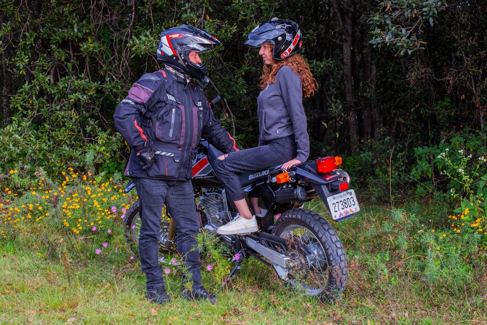 a man and a woman standing next to a motorcycle