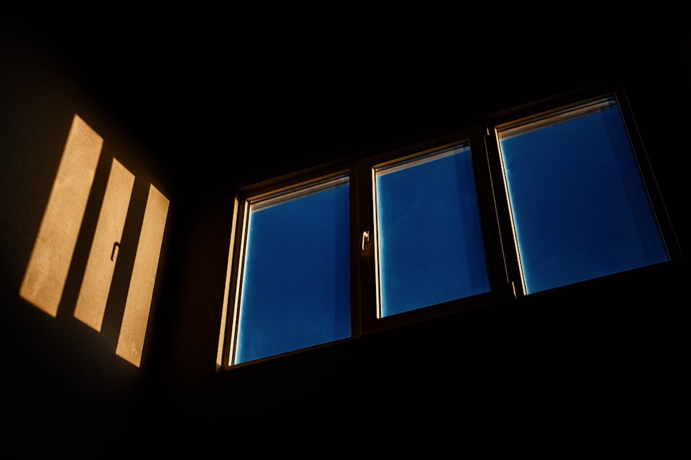 a dark room with three windows and a blue sky