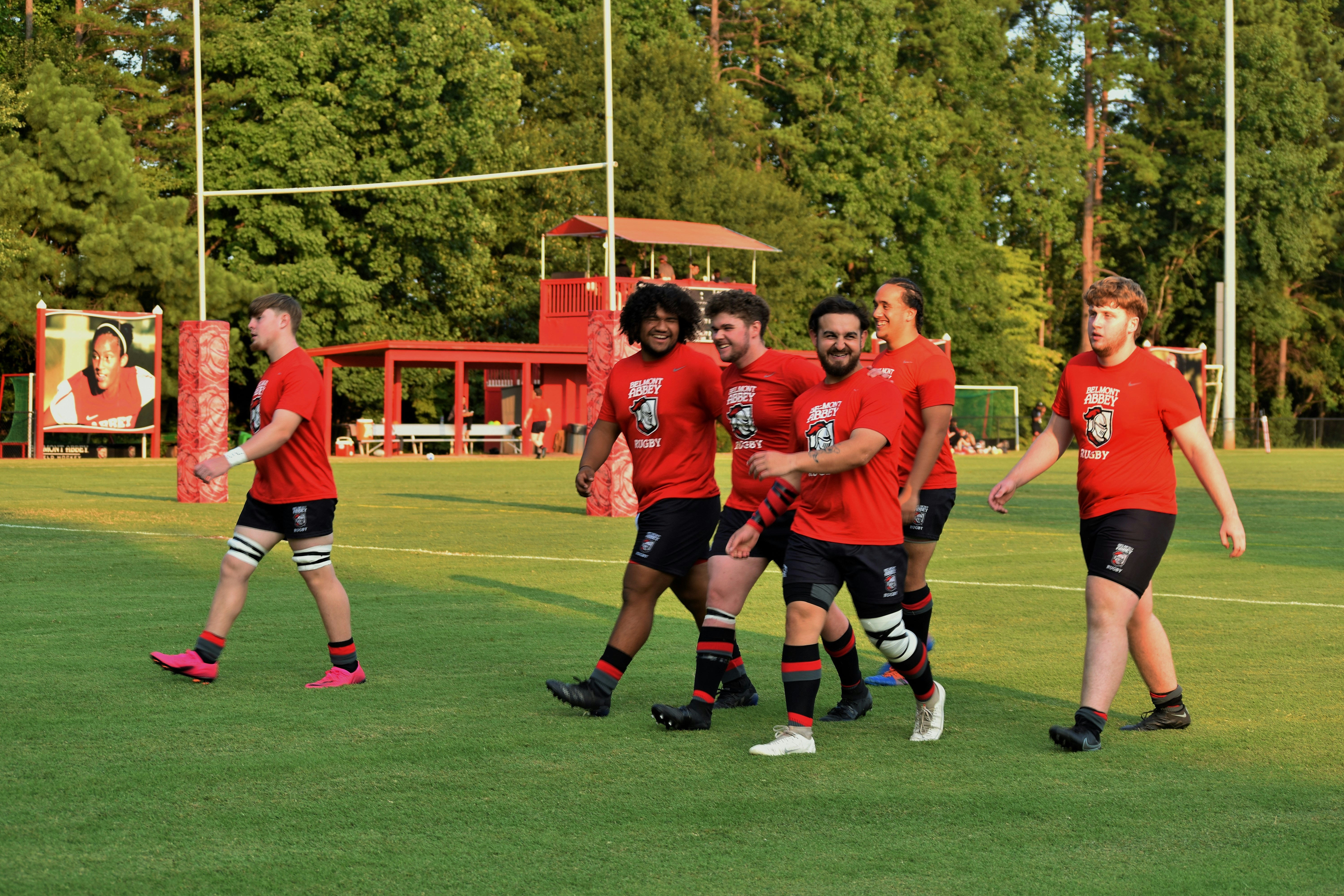 A group of laughing rugby players make their way to the locker rooms before a game starts after warming up.