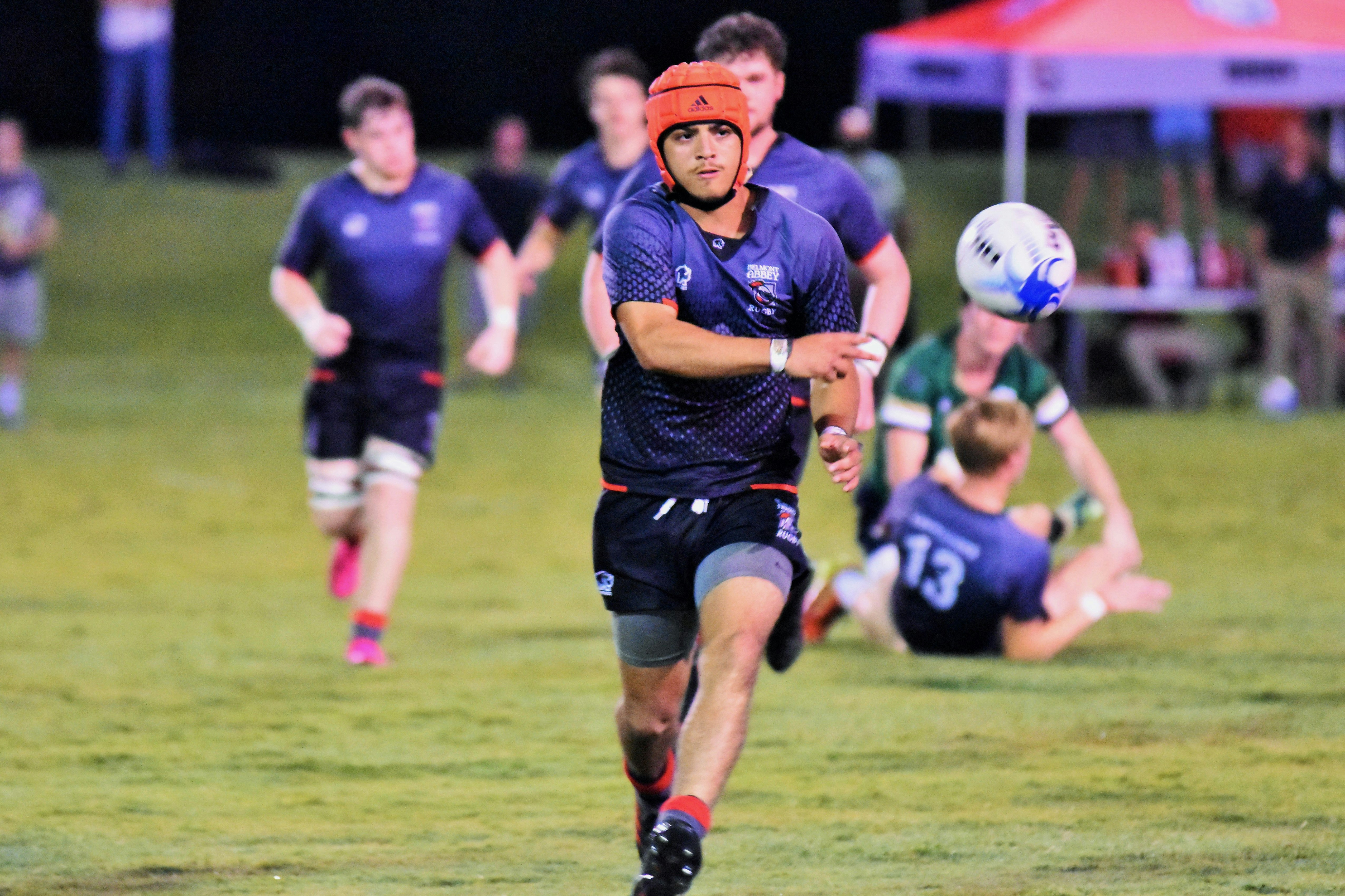 A Belmont Abbey College player throws the ball to a teammate during a night rugby game in Gastonia.