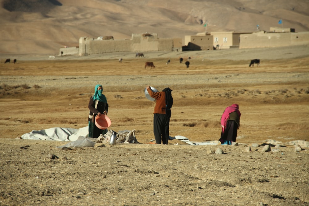 a group of people standing on top of a dirt field