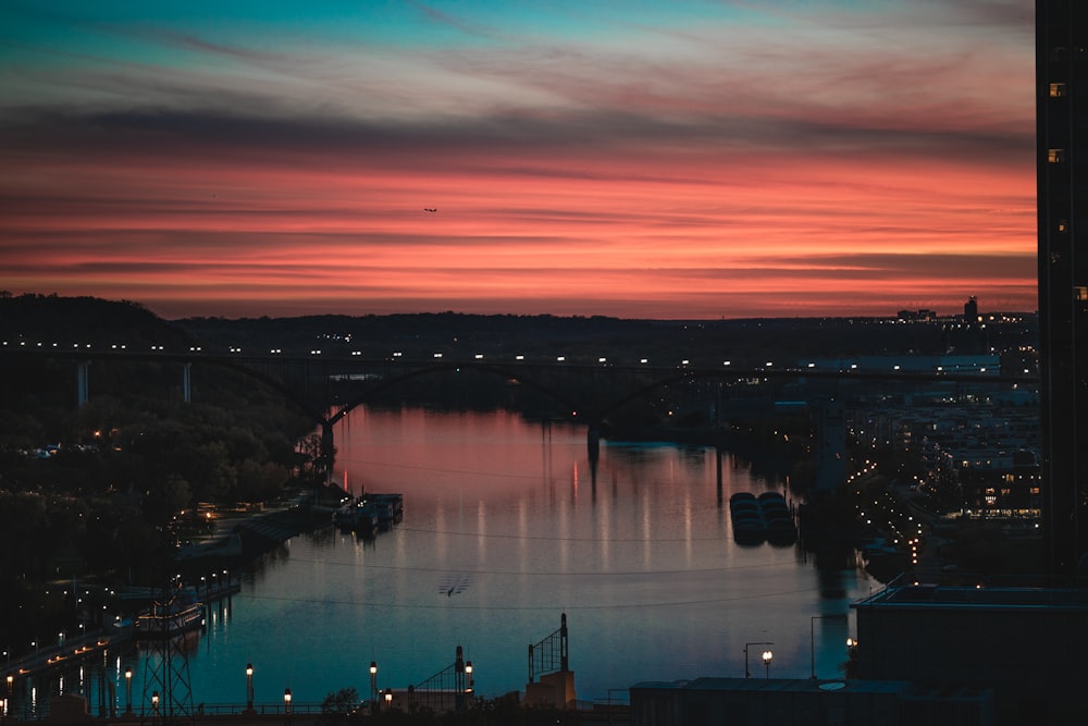 a sunset view of a river with a bridge in the distance