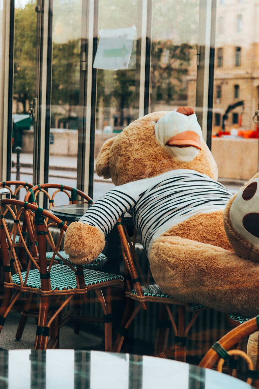 a teddy bear sitting on a chair in a cafe