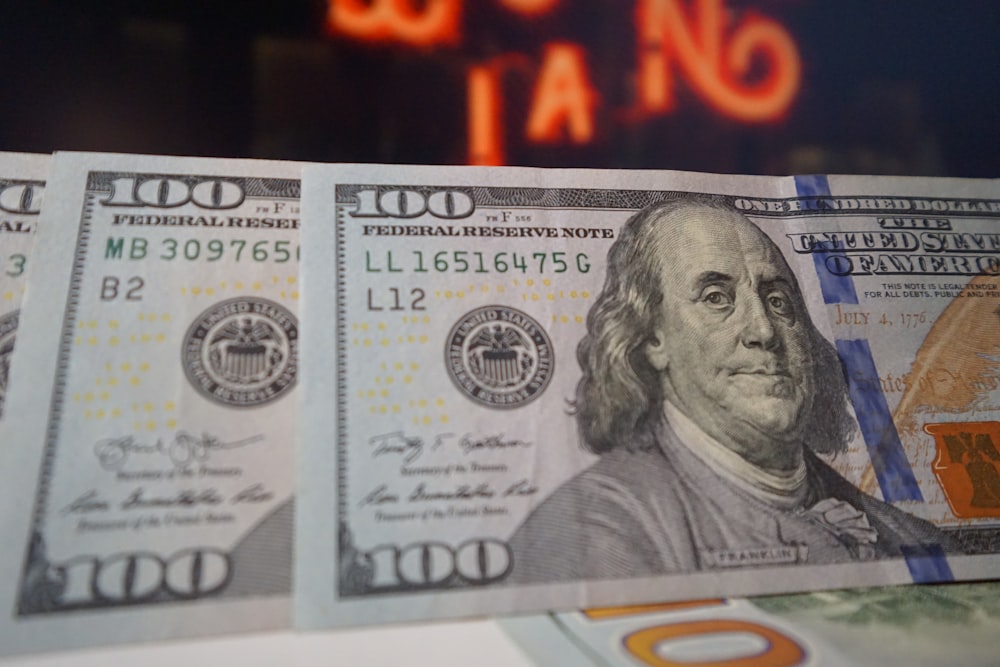 Una pila di banconote da venti dollari con un'insegna al neon sullo sfondo
