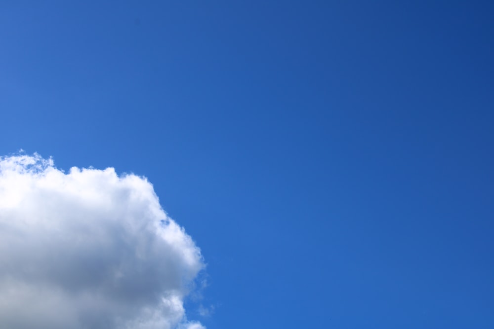 a plane flying high in the sky with a cloud