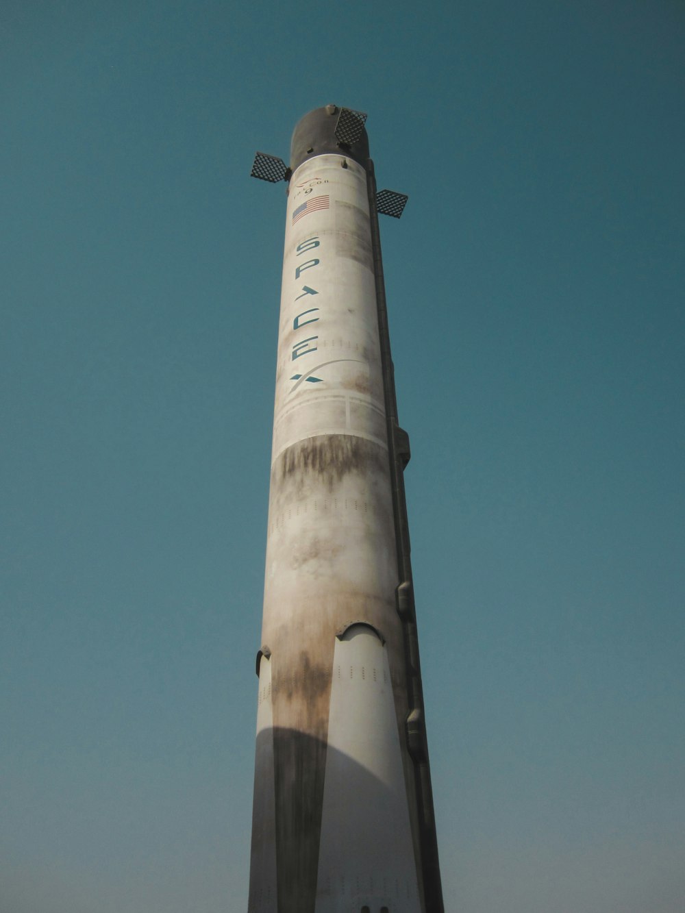 a very tall white rocket sitting on top of a field