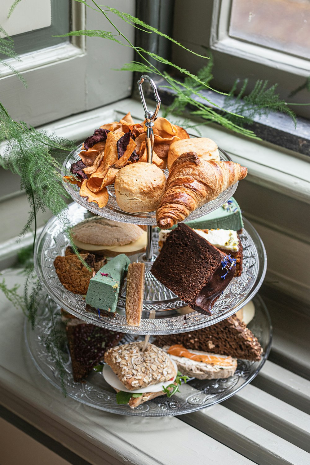 a three tiered tray of food on a window sill