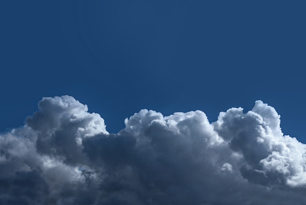 a plane flying through a cloudy blue sky