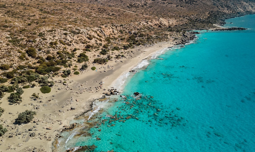 an aerial view of a beach with clear blue water