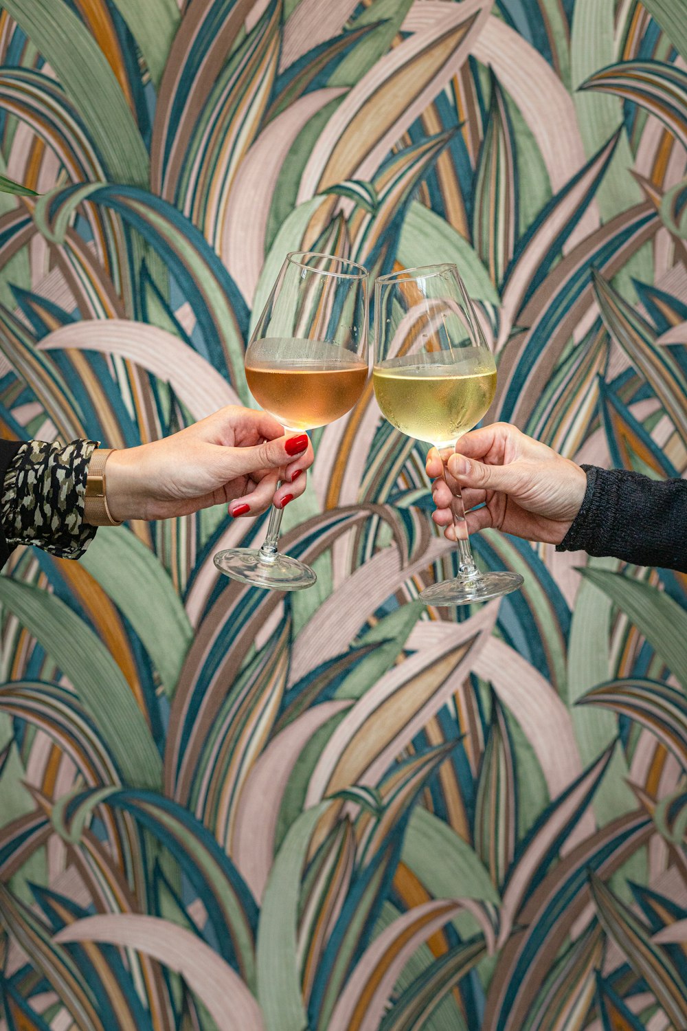 two people holding glasses of wine in front of a wallpaper