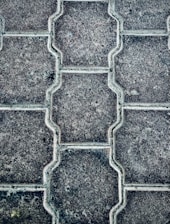 Close-up of workers laying paving stones on a driveway under clear daylight.