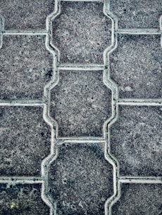 Close-up of workers laying paving stones on a driveway under clear daylight.