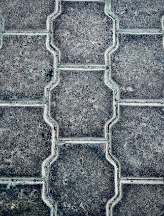 Large black background with white text overlaid, showing a close-up of textured interlocking paving stones.