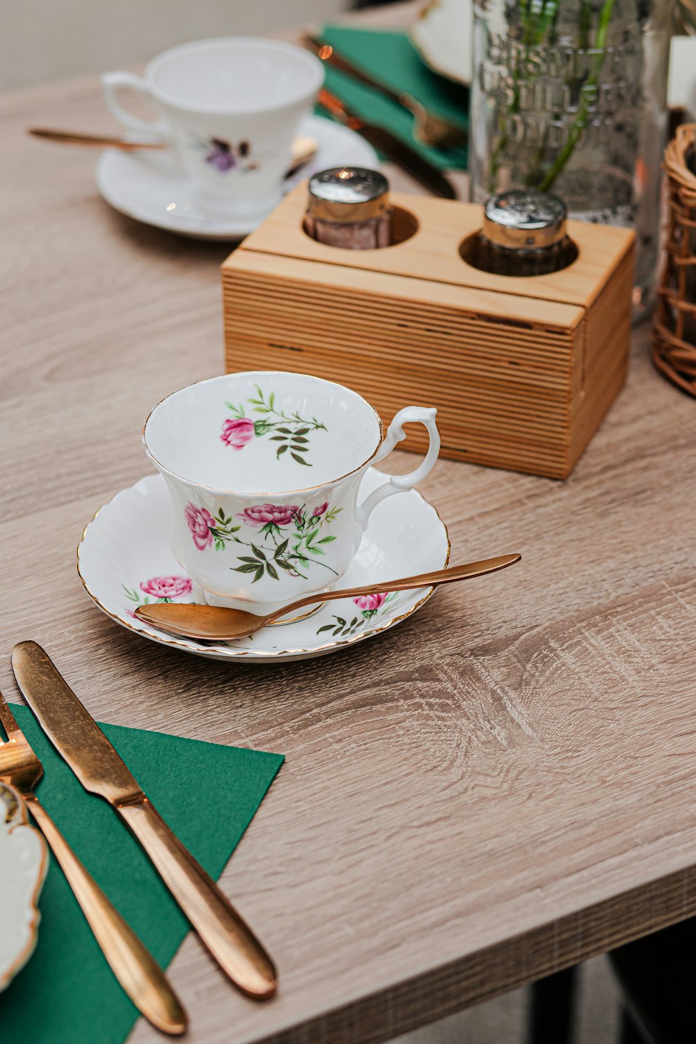 a wooden table topped with a tea cup and saucer
