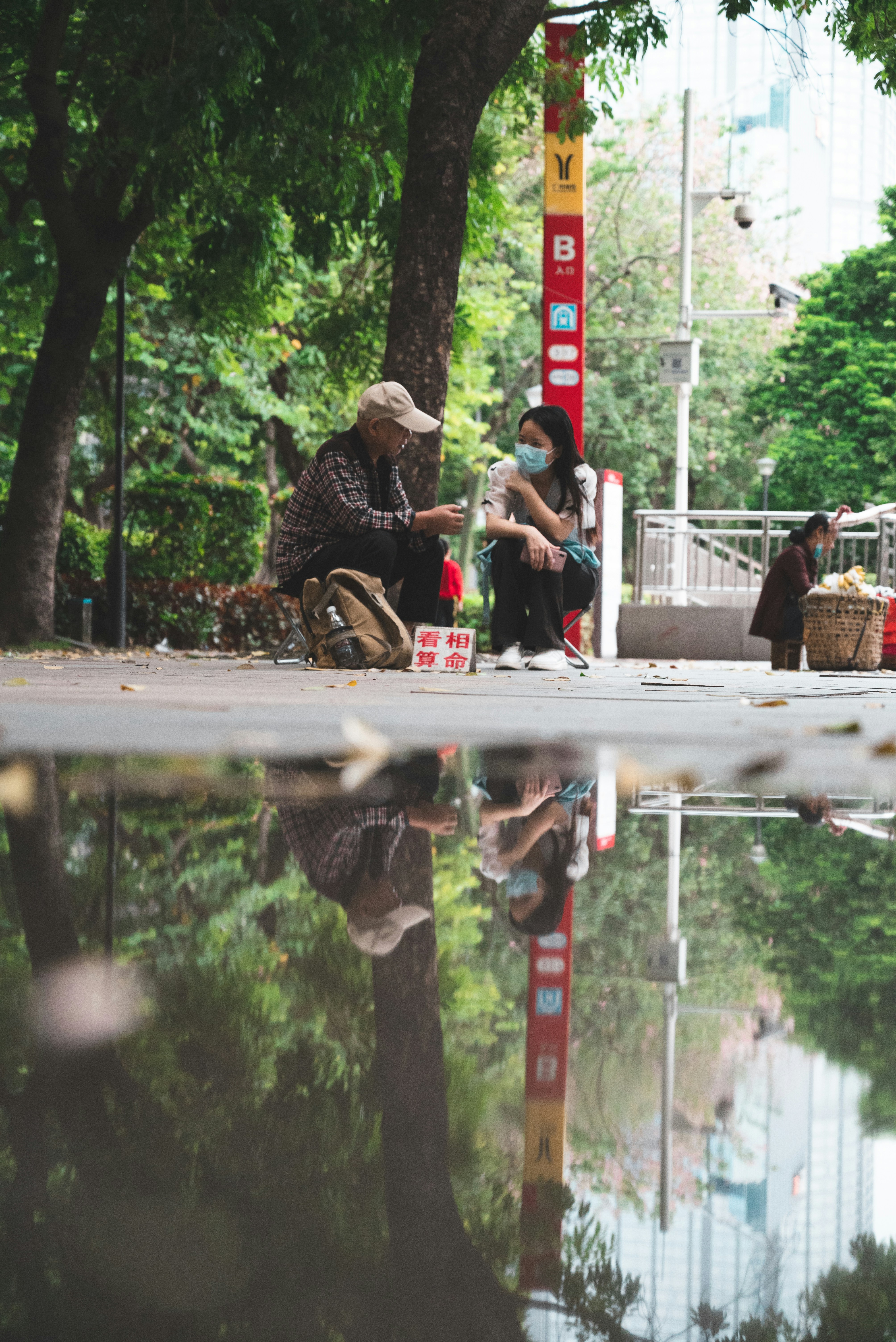 Un par de personas sentadas en un banco junto a un estanque