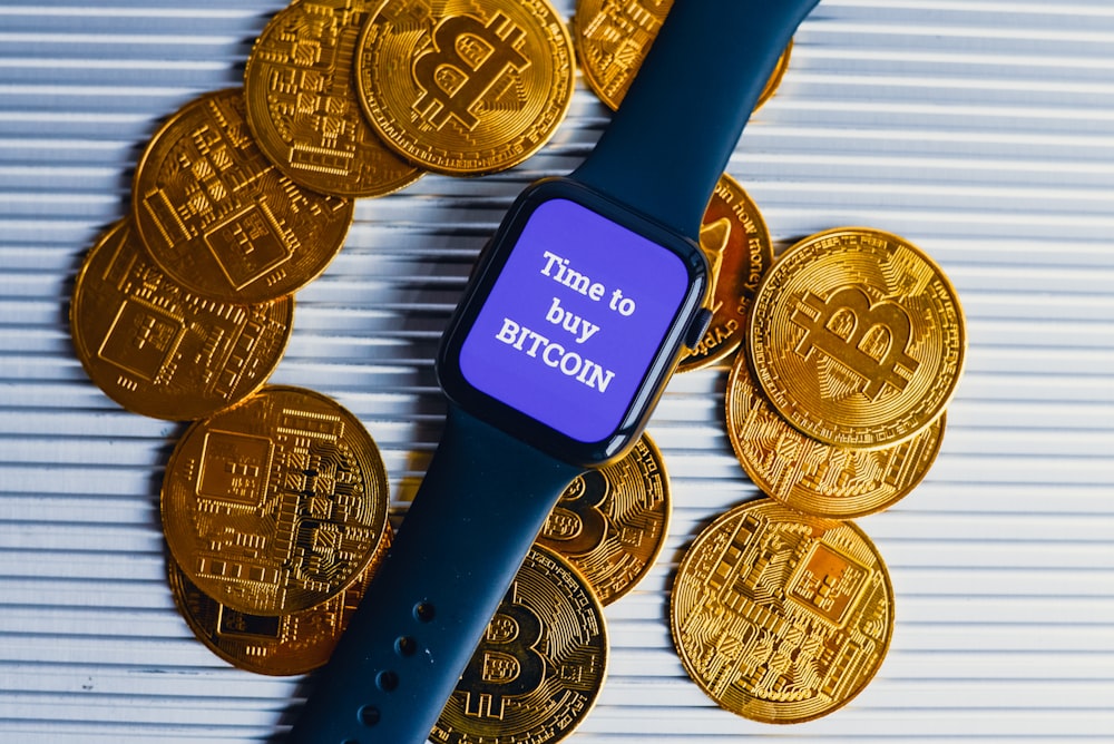 a smart watch sitting on top of a pile of gold coins