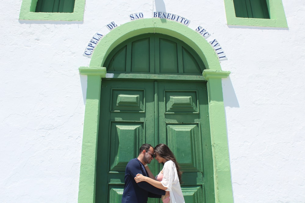 a bride and groom kissing in front of a green door