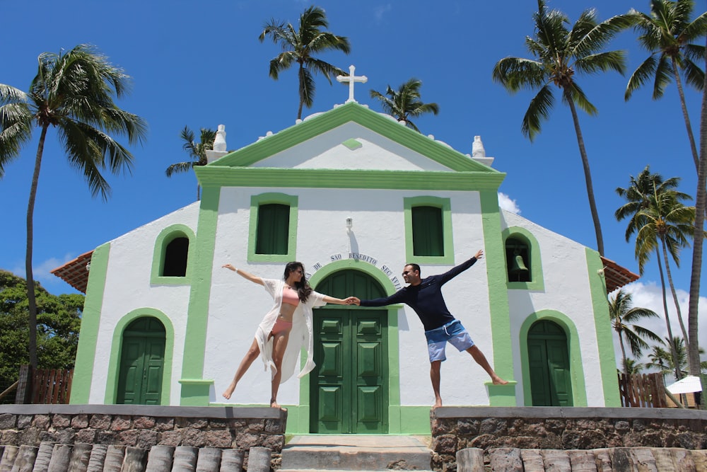 a man and a woman jumping in front of a church