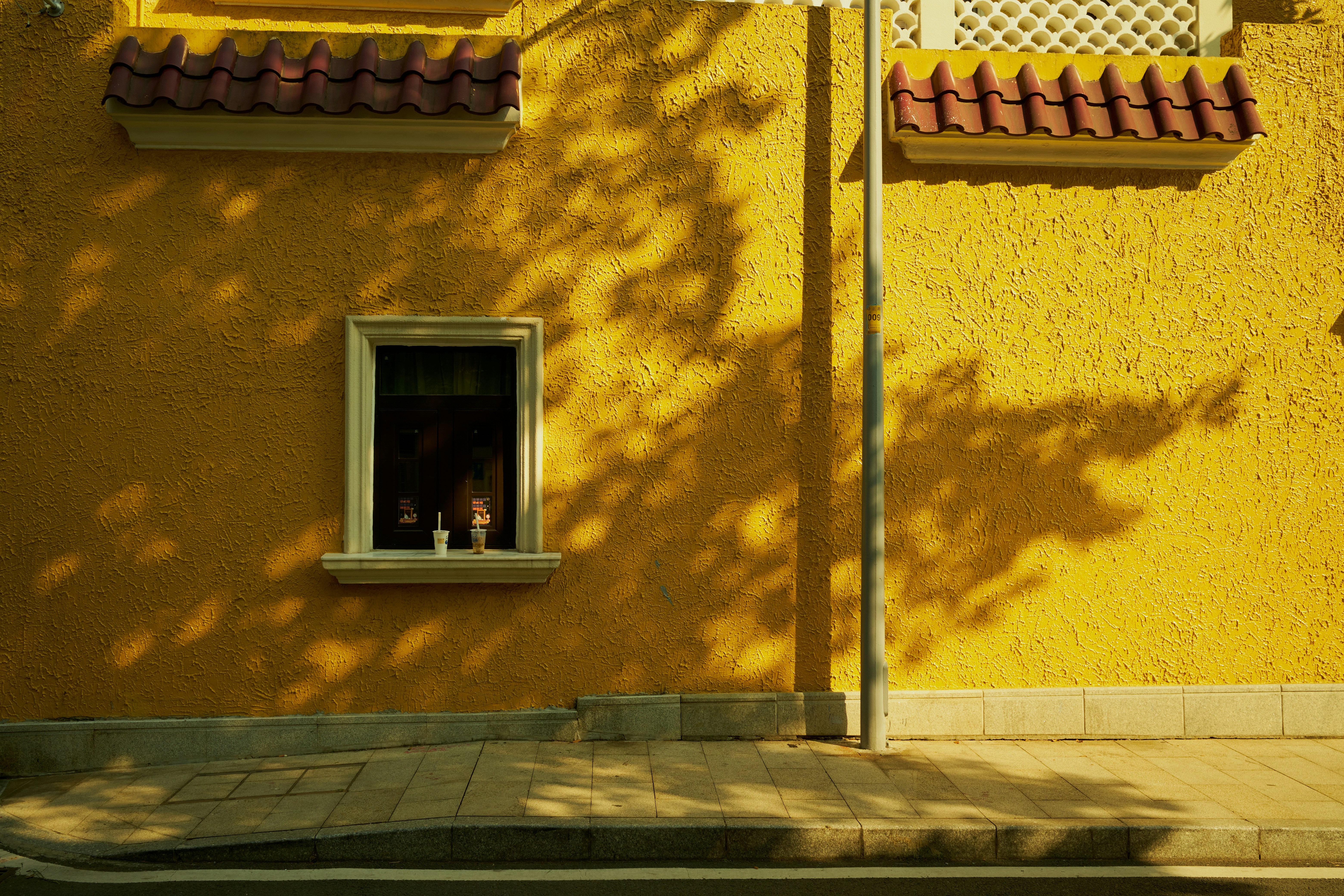 a yellow building with a red roof and a window