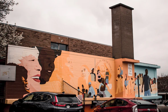 A vibrant community art workshop with diverse people creating colorful murals together.