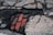 Cracked pavement exposes red bricks beneath, with surrounding asphalt showing signs of wear and decay.