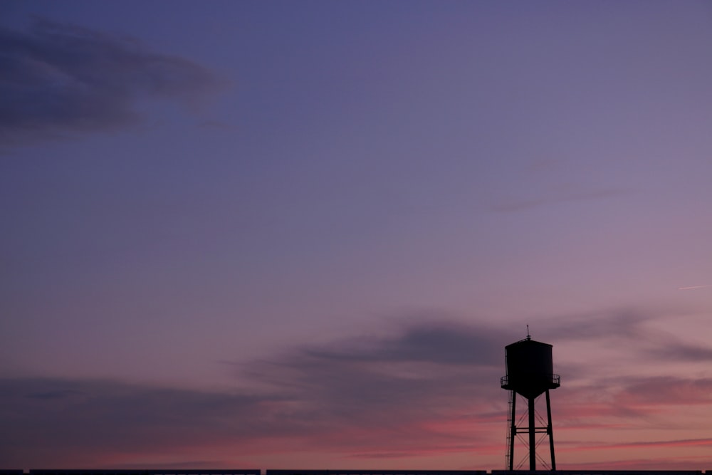 a water tower is silhouetted against a purple sky