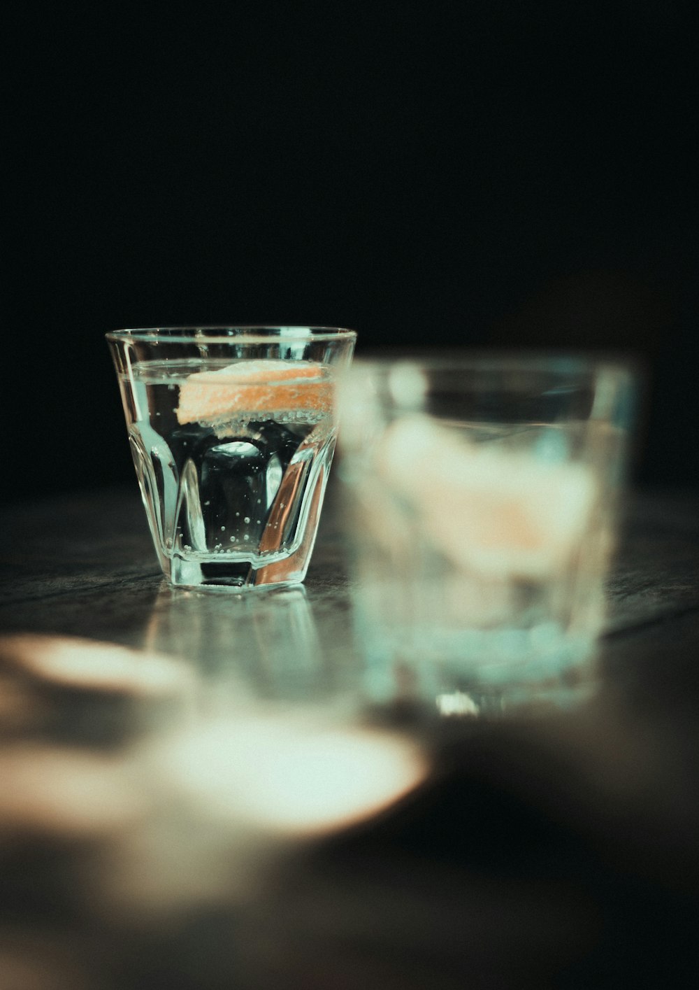 Un vaso de agua sentado encima de una mesa de madera