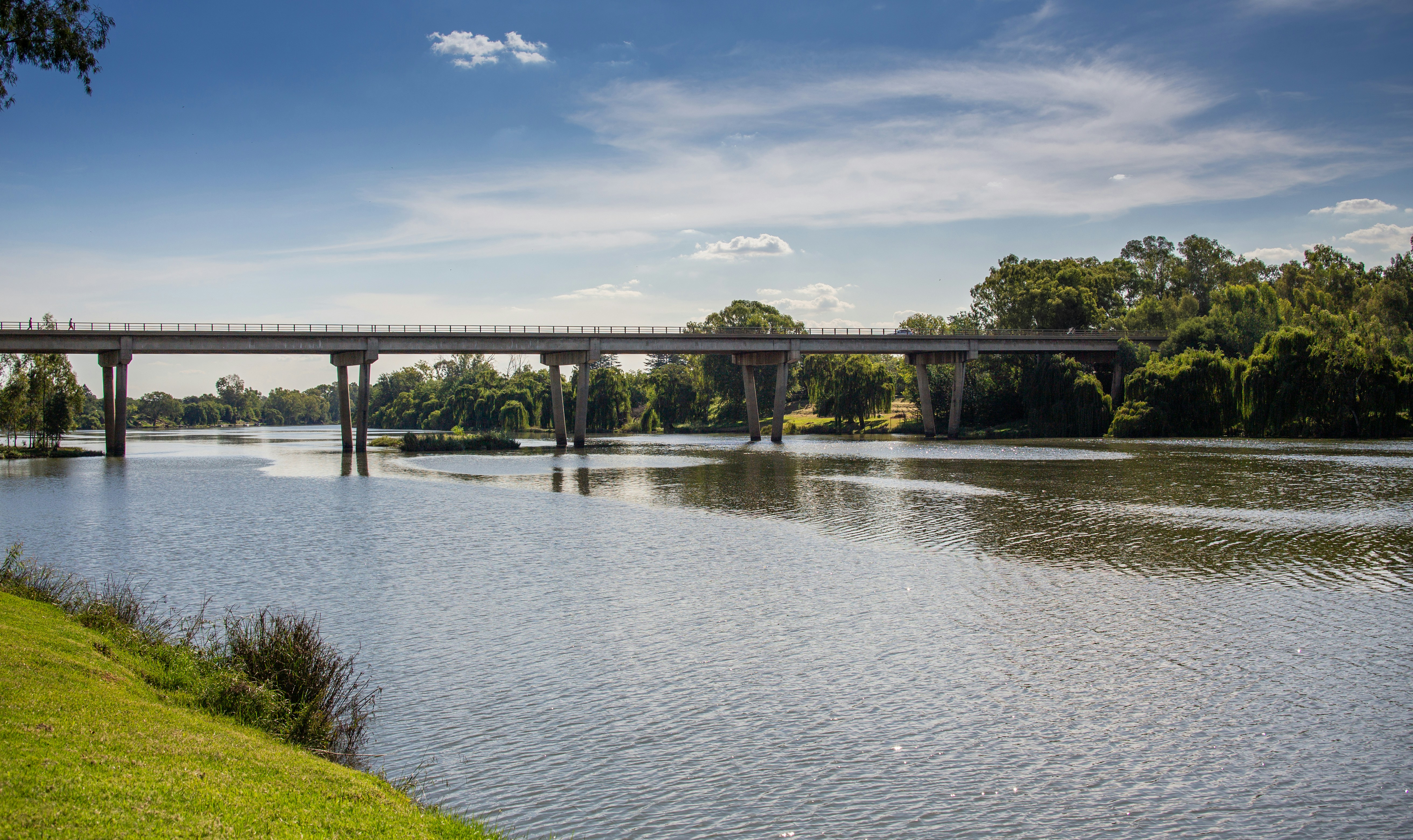 a bridge over a body of water next to a lush green field