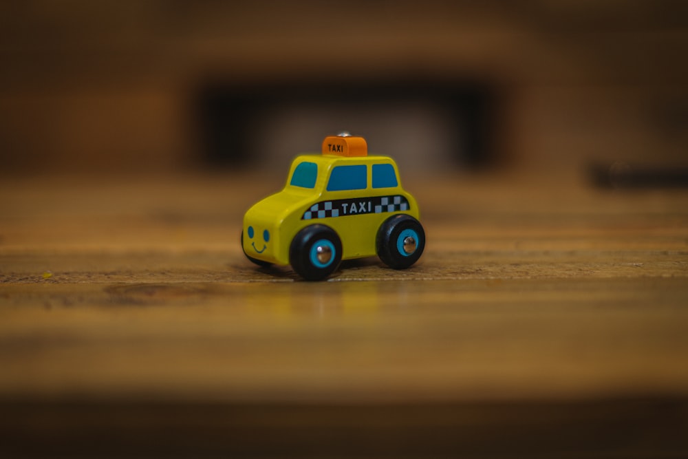 um carro de brinquedo amarelo sentado em cima de uma mesa de madeira