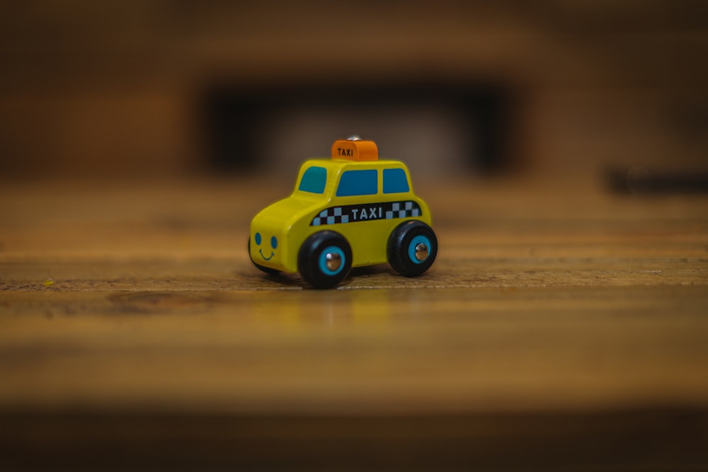 a yellow toy car sitting on top of a wooden table