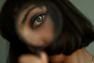 A close-up of a dermatologist examining a patient's skin with a magnifying glass.