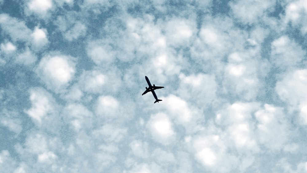 a plane flying through a cloudy blue sky