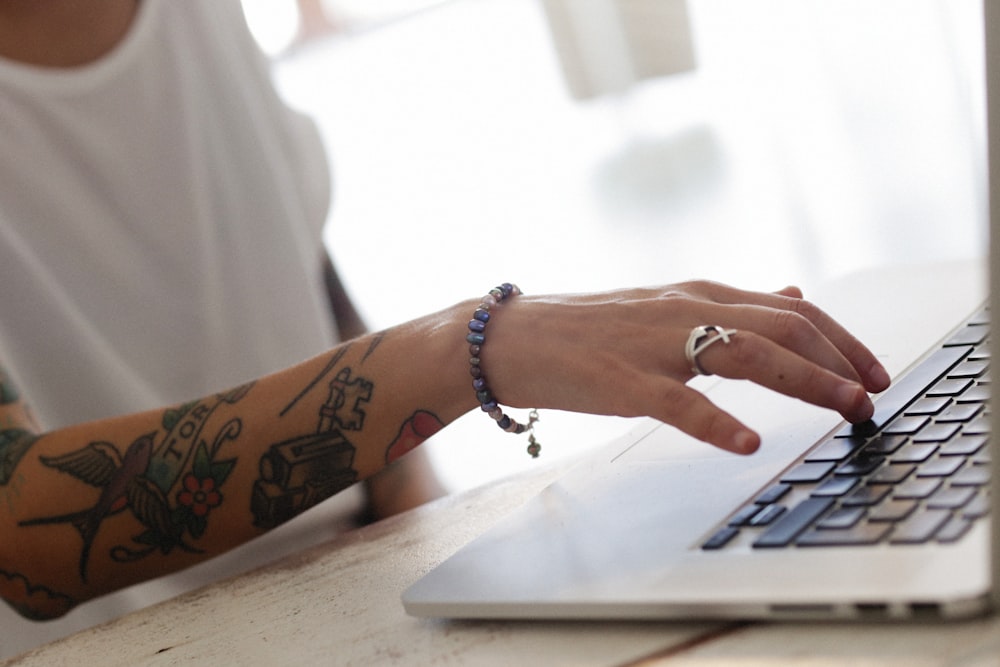 a person with a tattoo on their arm using a laptop