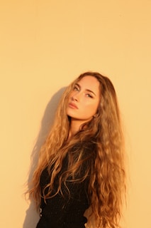 Hands delicately styling thick, vibrant hair with a backdrop of warm, inviting tones.