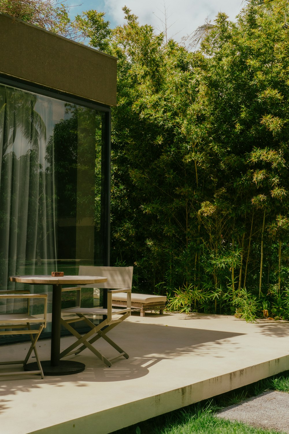 a patio with a table and chairs next to a forest