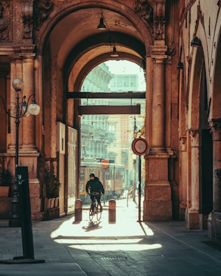 a man riding a bike down a street next to a tall building