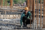 Smiling construction worker inspecting a modern building site in blue hard hat.